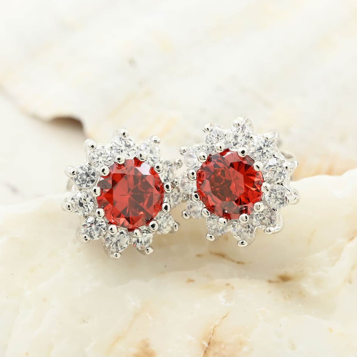 Simulated Red and White Diamond Halo Stud Earrings in Silvertone image number 1