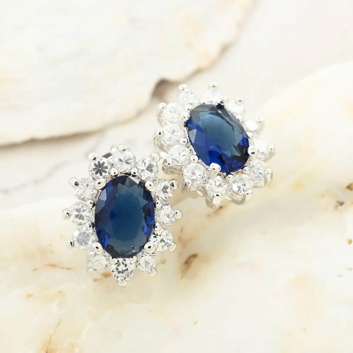 Simulated Blue and White Diamond Halo Stud Earrings in Silvertone image number 1